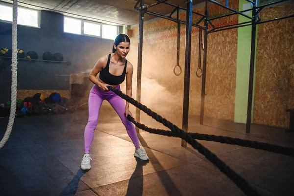 Mujer atlética caucásica haciendo ejercicio con cuerdas en el gimnasio . — Foto de Stock