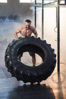 Spor salonunda lastik çeviren genç güçlü adam.