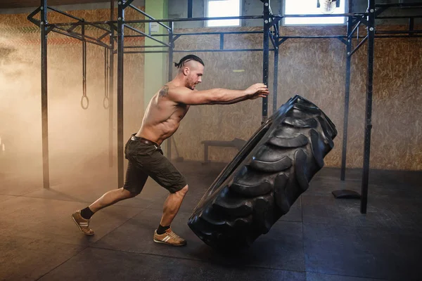 年轻的强壮男人在健身房里翻转轮胎. — 图库照片
