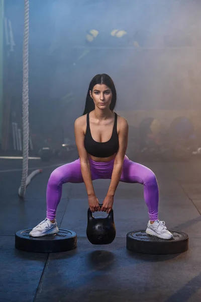 Joven mujer en forma haciendo ejercicio con pesas en el gimnasio . —  Fotos de Stock