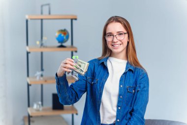 Denim gömlek ve gözlük genç kız yakın Abd doları ile küçük alışveriş sepeti tutar.