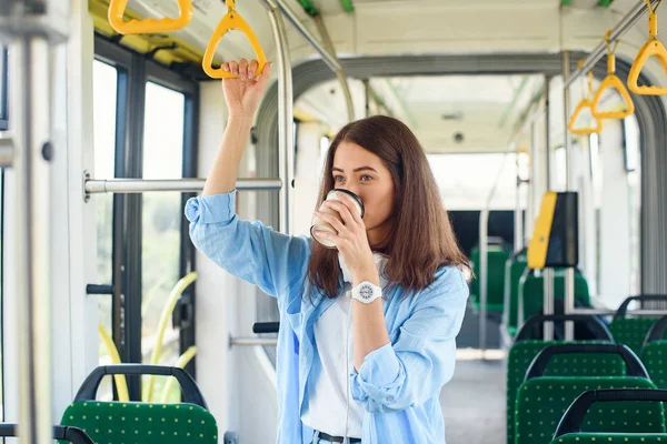Mavi bok güzel kadın toplu taşıma sürüş sırasında kahve içiyor.