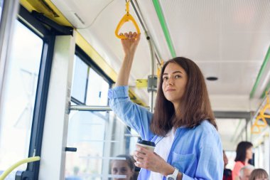 Güzel genç kadın şehir otobüsü veya tramvay lezzetli kahve içecekler. Toplu taşıma kavramı.