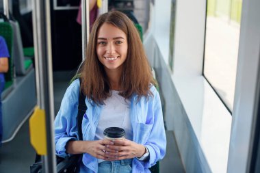 Güzel genç kadın şehir otobüsü veya tramvay lezzetli kahve içecekler. Toplu taşıma kavramı.
