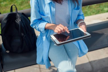 Kadın el bir toplu taşıma istasyonunda beklerken bir tablet kullanır.
