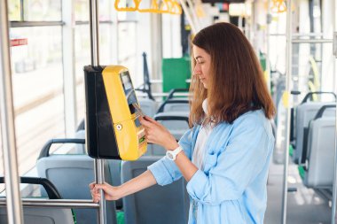 Genç kadın tramvay veya metro toplu taşıma için banka kartı ile öder.