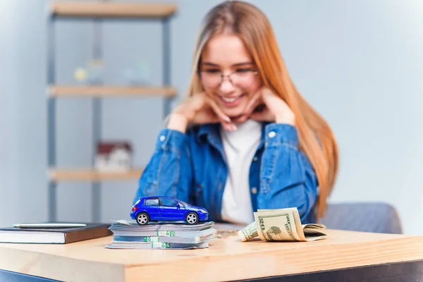 Beautiful young woman counts money savings to buy her own vehicle.