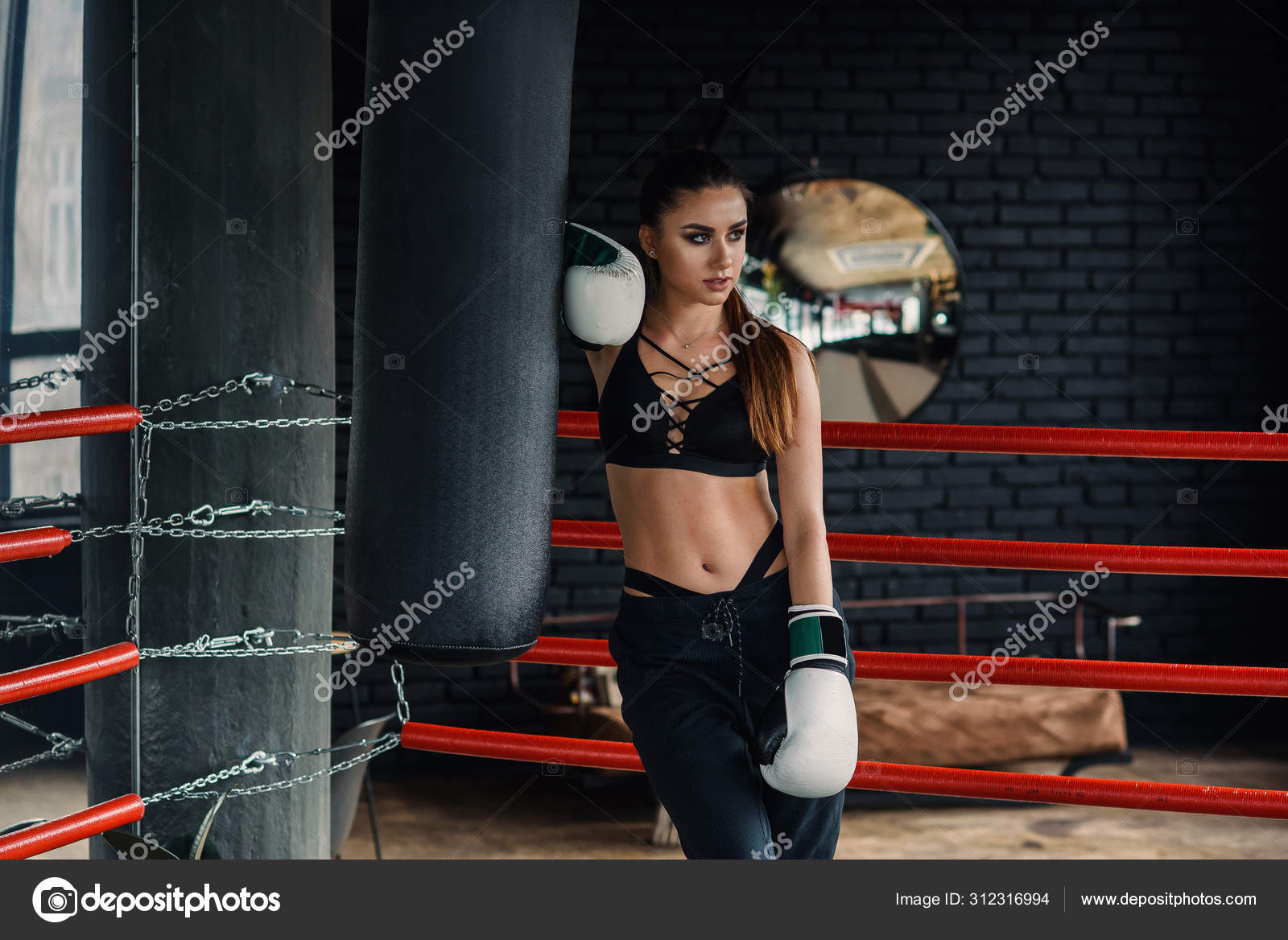 Mujer deportiva en ropa deportiva negra y guantes de boxeo blancos tienen un descanso despues de