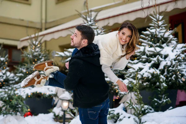Ευτυχισμένο νεαρό ζευγάρι που διασκεδάζει στο φόντο του χειμερινού αστικού τοπίου του χριστουγεννιάτικου δέντρου με φώτα. Χειμερινές διακοπές, Χριστούγεννα και Πρωτοχρονιά έννοια. — Φωτογραφία Αρχείου
