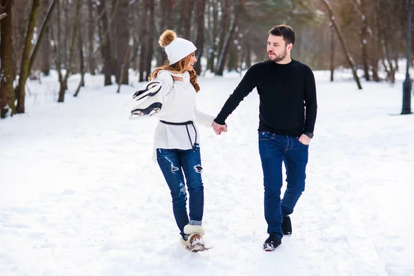 Couple amoureux marchant sur un rendez-vous dans un parc d'hiver. Sur le dos des filles accrochant une paire de patins . — Photo