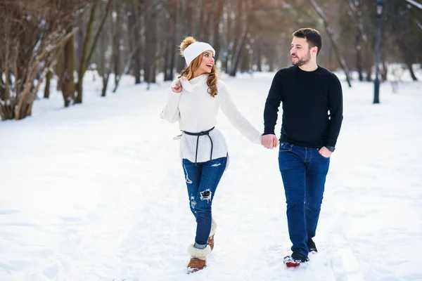 Couple amoureux marchant sur un rendez-vous dans un parc d'hiver. Sur le dos des filles accrochant une paire de patins . — Photo