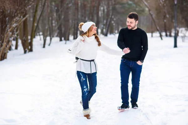 Couple amoureux marchant sur un rendez-vous dans un parc d'hiver. Sur le dos des filles accrochant une paire de patins . — Photo