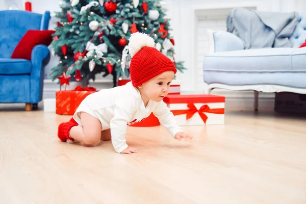 Adorabile bambino sorridente strisciare sul parquet per i regali di Natale vicino a sua madre che si siede sul pavimento . — Foto Stock