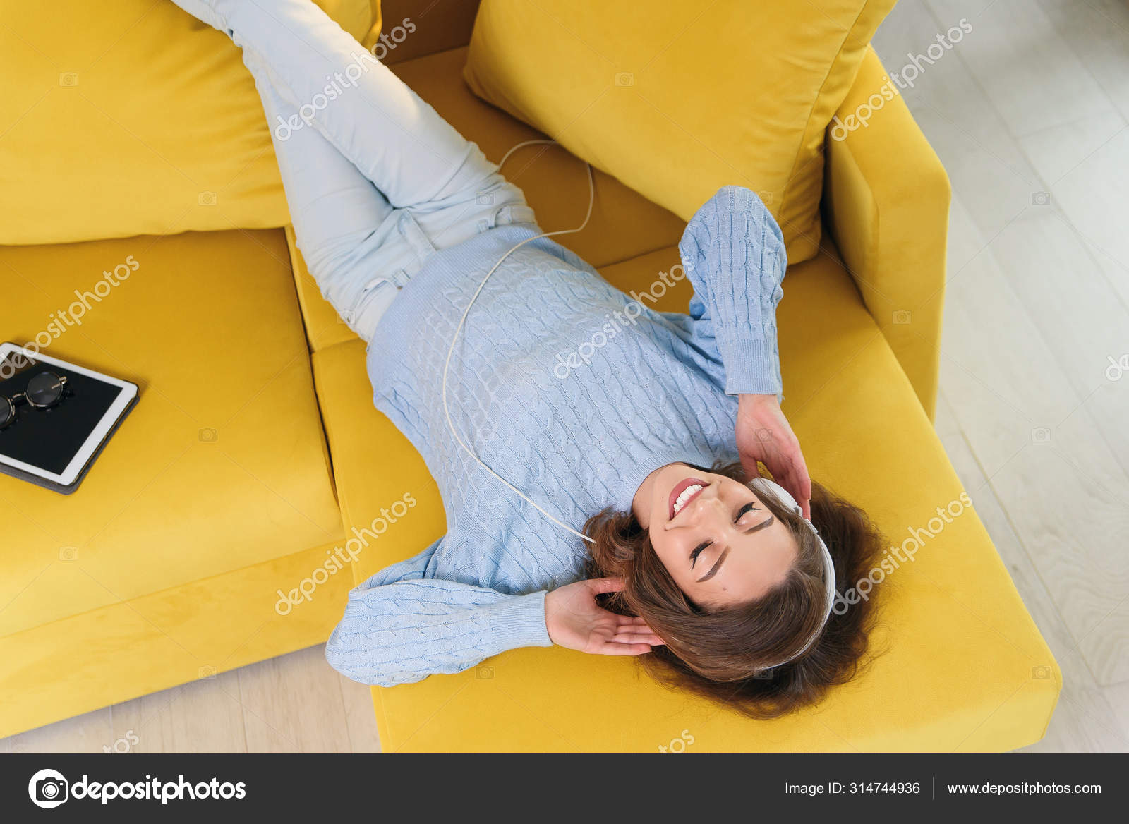 Menina sorridente, deitada no sofá confortável, desfrutando de