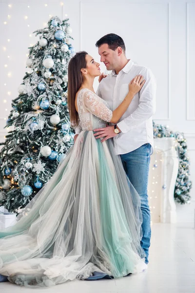 Ζευγάρι ερωτευμένο στέκονται μαζί κοντά στο χριστουγεννιάτικο δέντρο και κοιτάζονται. — Φωτογραφία Αρχείου