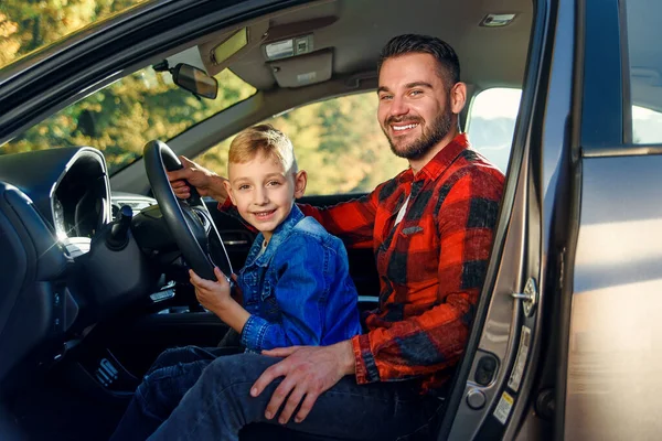 Father gives his son driving lessons, enjoying time together