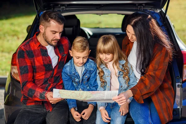 Close-up de família agradável alegre que gethering em suas férias com crianças adolescentes e usando o mapa da estrada para escolher o caminho certo no carro — Fotografia de Stock