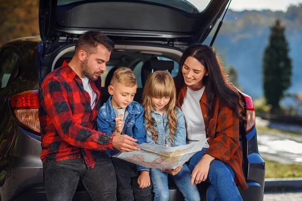 Close-up de família agradável alegre que gethering em suas férias com crianças adolescentes e usando o mapa da estrada para escolher o caminho certo no carro — Fotografia de Stock