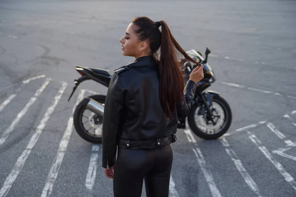 在摩托车上的地下停车场里穿着皮夹克的长发女孩 — 图库照片