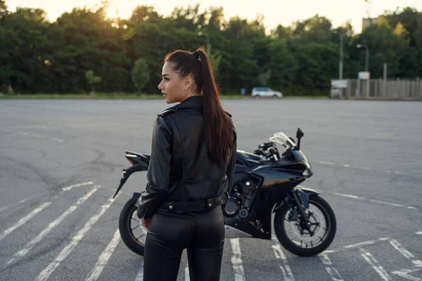 Дівчина з довгим волоссям у шкіряній куртці на підземній парковці на мотоциклі — стокове фото