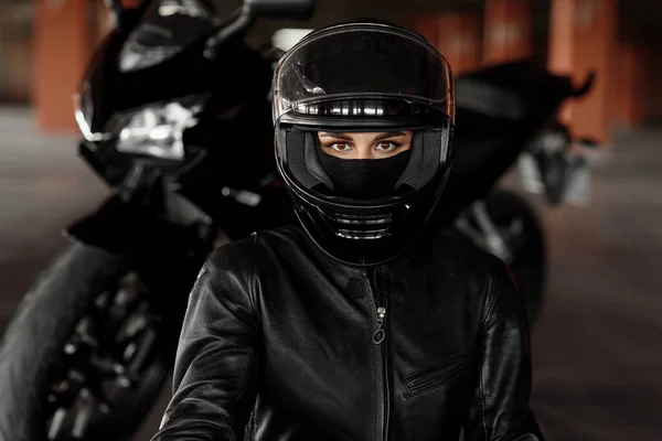 Horizontale Aufnahme einer unkenntlichen Motorradfahrerin, die mit ihrem Enduro-Motorrad oder Chopper in stilvoller Lederkleidung und Schutzausrüstung unterwegs ist, verschwommene Lichter und Autos im Hintergrund — Stockfoto