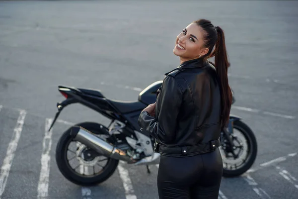 Девушка с длинными волосами в кожаной куртке на подземной парковке на мотоцикле — стоковое фото