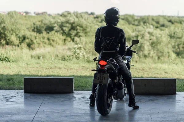 Lviv, Ucrânia - 01.07.2020: Uma menina de equipamento de proteção preto em um estacionamento subterrâneo em uma motocicleta Honda preta. — Fotografia de Stock