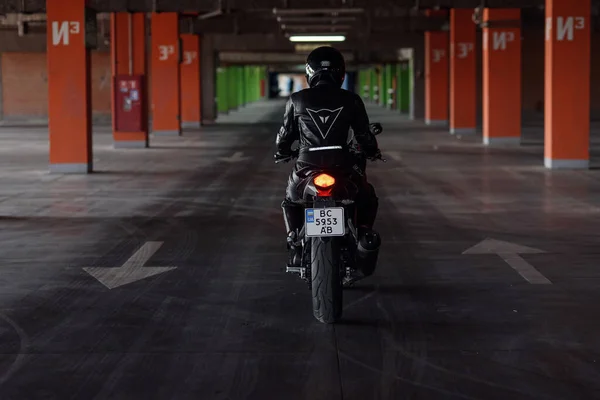 Lviv, Ucrania - 01.07.2020: Una chica con equipo de protección negro en un estacionamiento subterráneo en una motocicleta Honda negra. —  Fotos de Stock