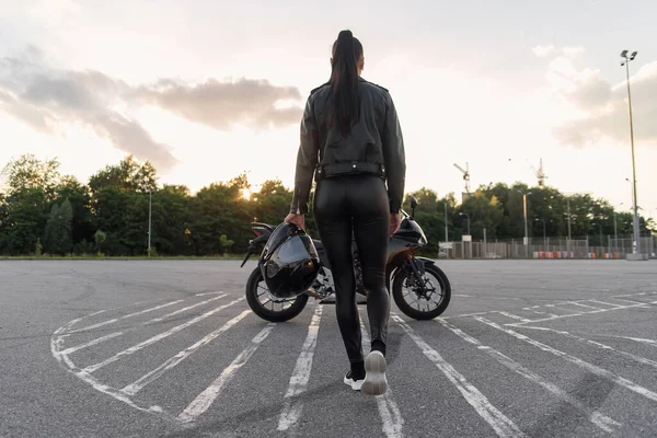 Дівчина з довгим волоссям у шкіряній куртці на підземній парковці на мотоциклі — стокове фото
