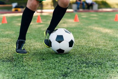 Detaylı futbolcu sahada topa vuruyor. Futbol oyuncuları antrenman yapıyor. Futbol geçmişini detaylandır. Yeşil çimenlikteki futbolcunun bacaklarına ve ayaklarına yakın dur.