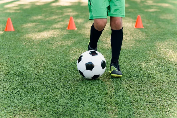 Detail fotbalista kopající míč na hřišti. Fotbalisti na tréninku. Detailní fotbalové pozadí. Zblízka nohy a nohy fotbalisty na zelené trávě — Stock fotografie