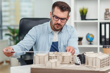 Bir inşaat projesinde çalışan yakışıklı Kafkas kıdemli mimar ve üzerinde çalıştığı modeli inceliyor..