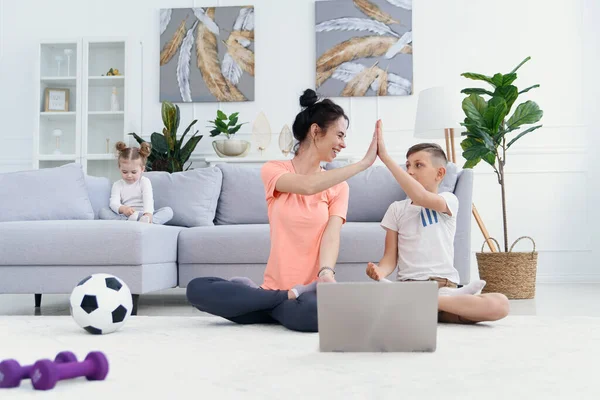 Mãe e filho praticam ioga com laptop em casa. Mãe com criança se exercitando de manhã. Conceito de estilo de vida saudável. — Fotografia de Stock