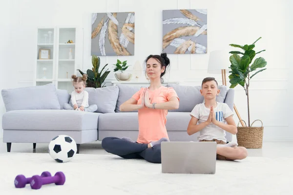 Mom and son practice yoga with laptop at home. Mother with child exercising in the morning. Healthy lifestyle concept.
