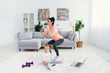 Annem evde sabah antrenmanı yaparken akıllı telefon kullanıyor. Annem spor yapıyor, sağlıklı yaşam tarzı konsepti..