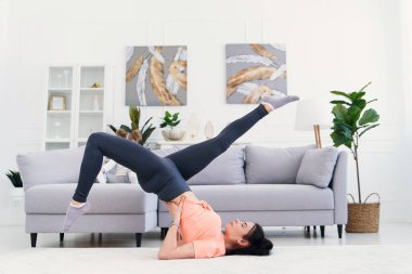 Genç anne esneme egzersizleri yapıyor ve küçük kızıyla evde yoga yapıyor. Sağlık ve spor konsepti.