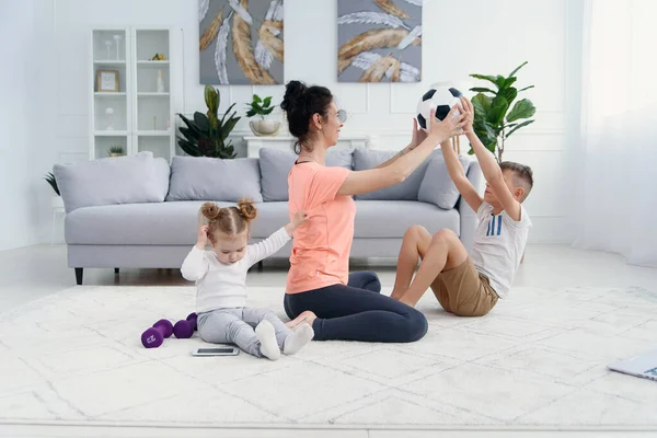 Mãe de esportes com filho fazendo exercício matinal em casa. Mãe e filho fazem exercícios juntos, conceito de estilo de vida familiar saudável — Fotografia de Stock