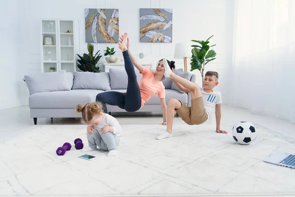 Sports mom with son doing morning work-out at home. Mum and son do exercises together, healthy family lifestyle concept