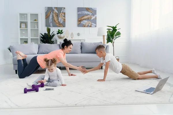 Mãe de esportes com filho fazendo exercício matinal em casa. Mãe e filho fazem exercícios juntos, conceito de estilo de vida familiar saudável — Fotografia de Stock