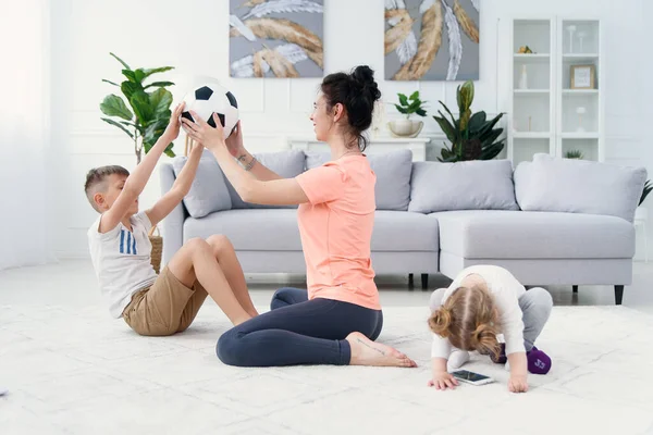 Jovem mãe desportiva com filho fazendo exercícios de treino matinal em casa. Conceito de estilo de vida familiar saudável — Fotografia de Stock