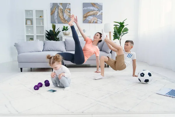 Jovem mãe esportiva com filho fazendo exercícios de aquecimento matinal em casa. Conceito de estilo de vida familiar saudável — Fotografia de Stock