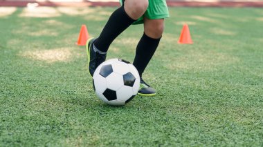 Futbolcu sahada topa vuruyor. Futbol oyuncuları antrenman yapıyor. Futbolcu ayaklarını çimenlerde tekmeleyip topa vuruyor..