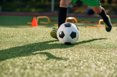 Futbolcu sahada topa vuruyor. Futbol oyuncuları antrenman yapıyor. Futbolcu ayaklarını çimenlerde tekmeleyip topa vuruyor..