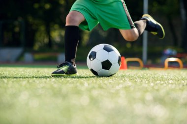 Futbolcu sahada topa vuruyor. Futbol oyuncuları antrenman yapıyor. Futbolcu ayaklarını çimenlerde tekmeleyip topa vuruyor..