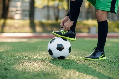Futbolcunun bacağını topa bağlayan ve futbol stadyumunda ayakkabı bağı bağlayan çizmesini kapat..