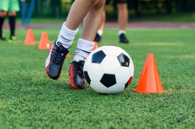 Futbolcu sahada topa vuruyor. Futbol oyuncuları antrenman yapıyor. Futbolcu ayaklarını çimenlerde tekmeleyip topa vuruyor..