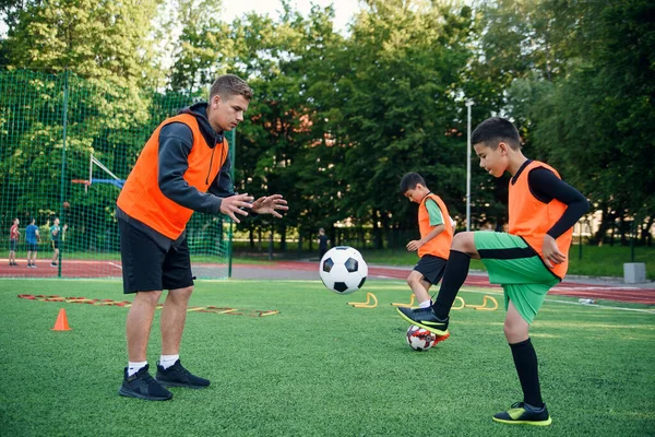 Young soccer coach instructs teen players. A young professional coach trains the ball kicks with young football players. — Stock Photo, Image