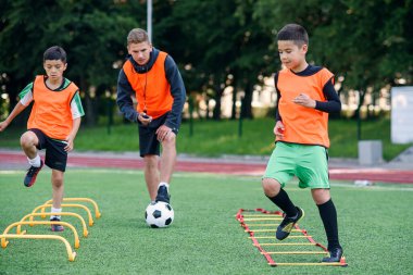 Futbol yaz kampı sırasında iki okul çocuğu sahada merdiven talimi yapıyor. Koçla yoğun futbol antrenmanı..
