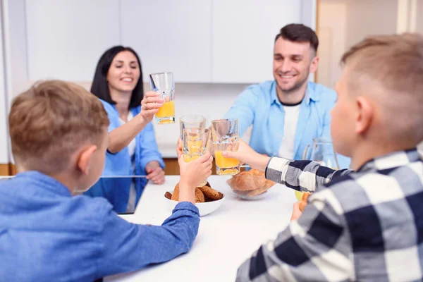 Família elegante alegre com dois filhos beber suco de laranja com bolos na cozinha moderna. Conceito de família feliz. — Fotografia de Stock