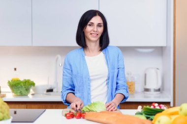Genç bayan, rahat modern mutfakta taze sebzelerden salata hazırlıyor. Sağlıklı gıda konsepti.